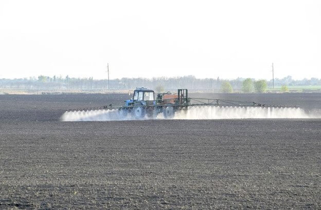 Farmer tending their crops with agrochemicals like pesticides, herbicides and fertilizer.