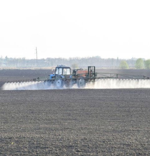 Tractor spraying herbicide chemicals on a field
